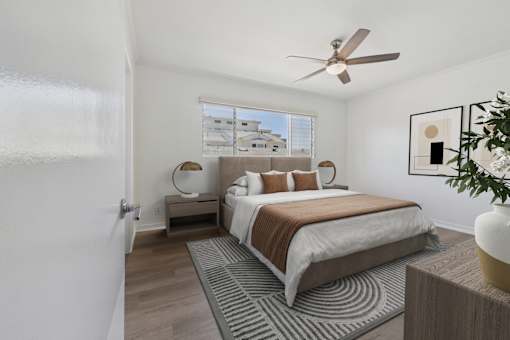 A bedroom with a bed, a bench, and a ceiling fan.