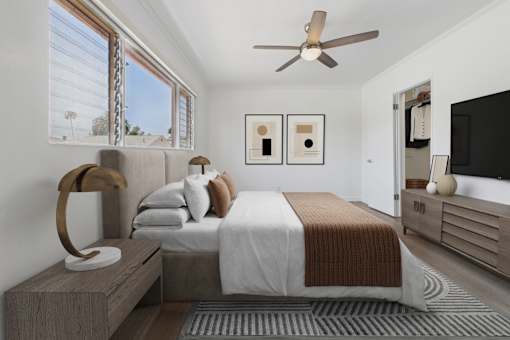 A bedroom with a bed, a bench, and a ceiling fan.