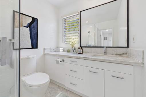 A bathroom with a white toilet, sink, and mirror.