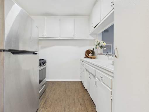 A kitchen with white cabinets and a stainless steel refrigerator.