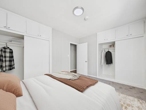 A bedroom with a bed, a mirror, and a wardrobe.
