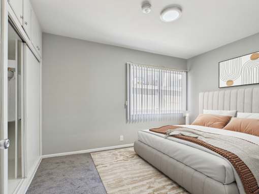 A bedroom with a large bed and a window with blinds.