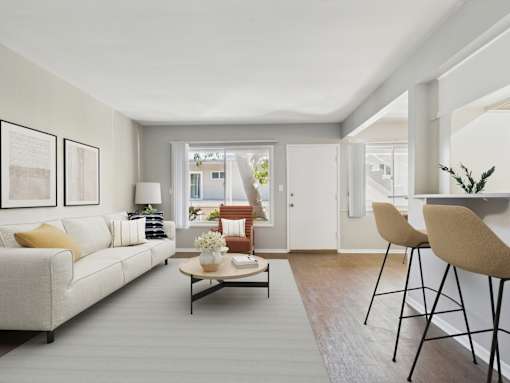A living room with a white couch, a coffee table, and a dining table with chairs.