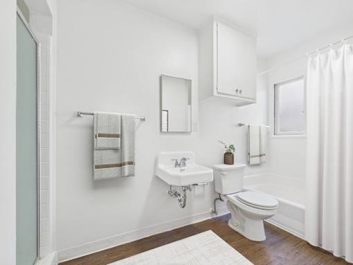 A white bathroom with a toilet, sink, and mirror.