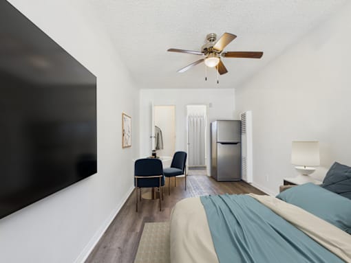 A bedroom with a bed, chair, and a ceiling fan.