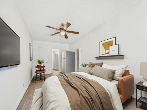 A bedroom with a bed, a ceiling fan, and a television.