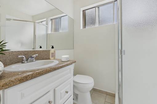 A bathroom with a sink, toilet, and a mirror.