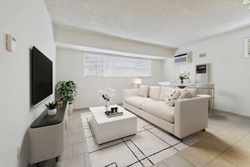 A living room with a white couch, a coffee table, and a television.
