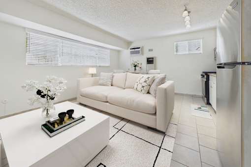 A white couch with a vase of flowers on a coffee table in a modern living room.