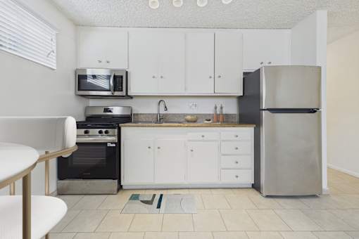 A kitchen with white cabinets and a black fridge.