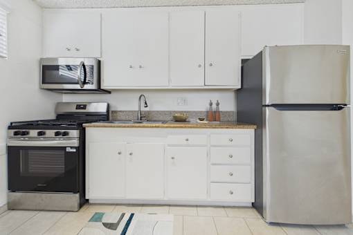 A kitchen with white cabinets and a black fridge.