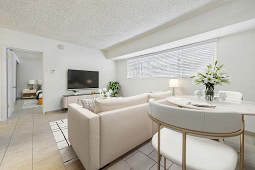 A living room with a beige couch, a white table, and a television.