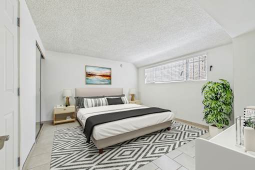 A bedroom with a bed, nightstand, lamp, and a painting on the wall.