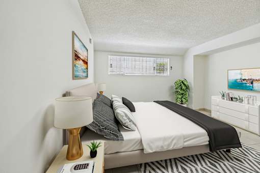 A bedroom with a bed, nightstand, and a painting on the wall.
