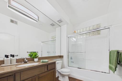 A bathroom with a toilet, sink, and mirror.