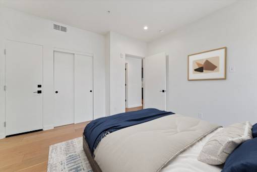 A bedroom with a bed, pillows, and a painting on the wall.