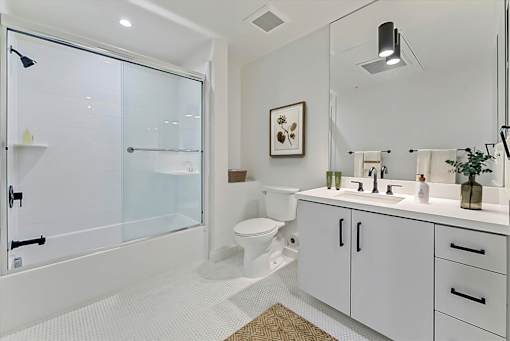 A white bathroom with a glass shower door and a white toilet.