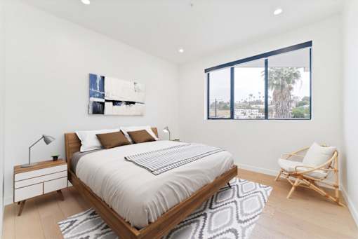 A bedroom with a large bed, a chair, and a painting on the wall.