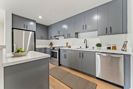 A modern kitchen with stainless steel appliances and grey cabinets.