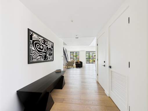 A long hallway with a bench and a painting on the wall.