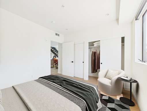 A bedroom with a bed, chair, and mirror.