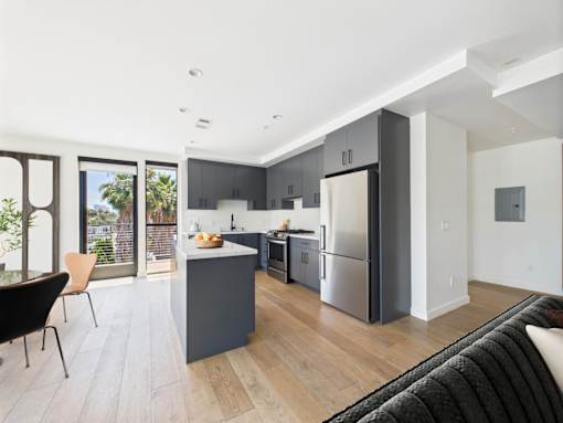 A modern kitchen with a black chair and a black couch.