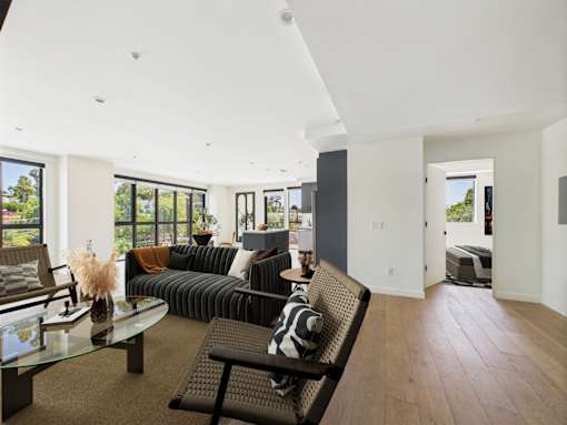 A modern living room with a glass table and a black couch.