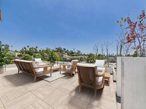 A patio with wooden furniture and a view of the city.