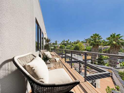 A balcony with a chair and a table with a plant on it.