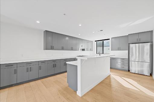 A modern kitchen with a white island and wooden floors.