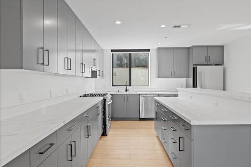 A modern kitchen with white countertops and grey cabinets.