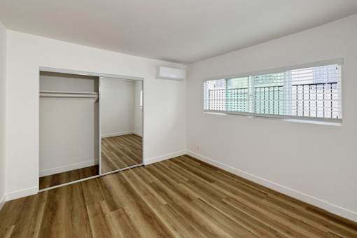 A room with wooden floors and a window with blinds.