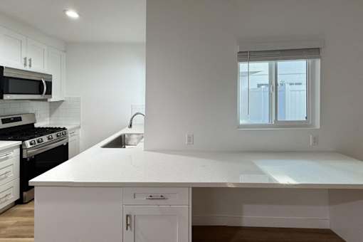 A modern kitchen with white cabinets and appliances.
