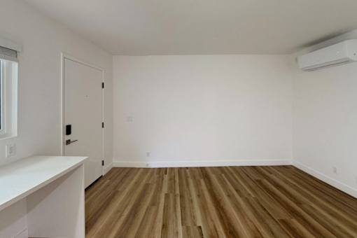 A room with wooden flooring and a white wall.