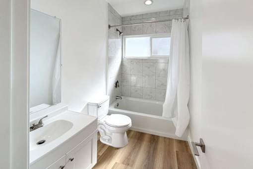 A white bathroom with a toilet, sink, and shower.