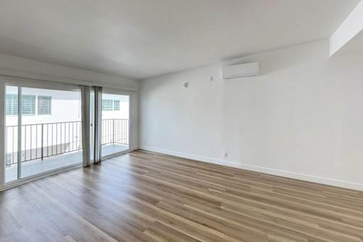 A room with wooden flooring and sliding glass doors.