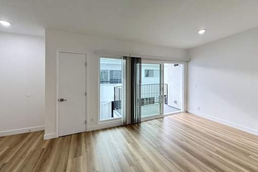 A room with a white door and a balcony with a black railing.