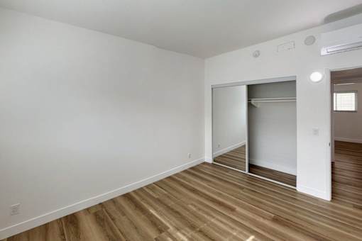 A room with a white wall and a wooden floor.
