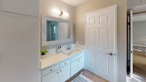 A white bathroom with a sink and mirror.