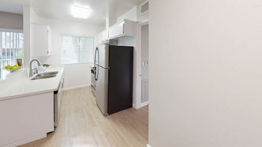 A black refrigerator in a kitchen with white cabinets.