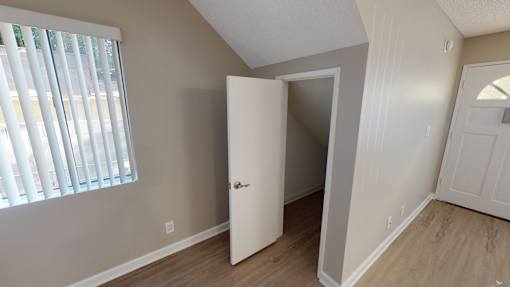 A room with a white door and a window with blinds.