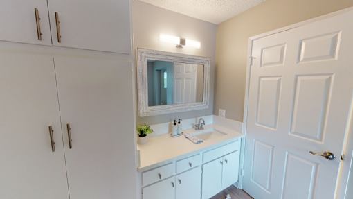 A white bathroom with a sink and mirror.