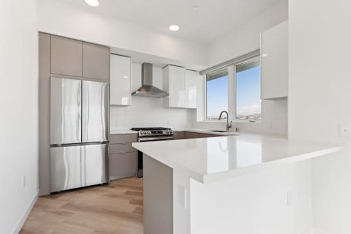 A modern kitchen with a stainless steel refrigerator and a white countertop.
