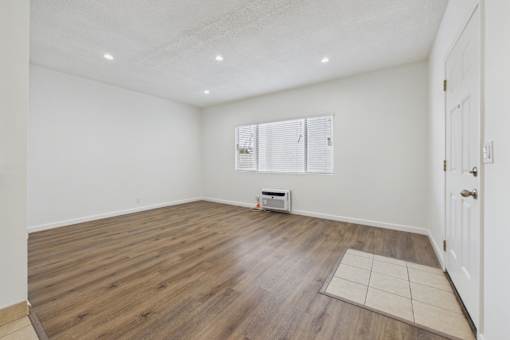 A room with wooden flooring and a window with blinds.