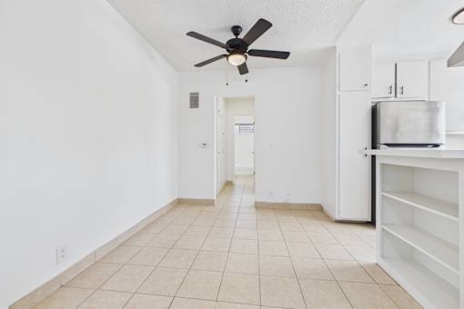 A kitchen area with a fan and a refrigerator.
