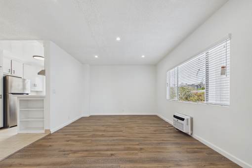 A room with a wooden floor and a window with blinds.