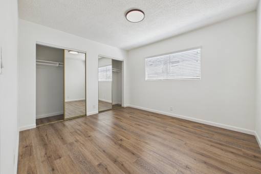 A room with a wooden floor and a large mirror on the wall.