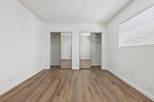 A room with a wooden floor and two closets.