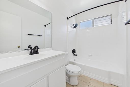 A white bathroom with a toilet, sink, and mirror.