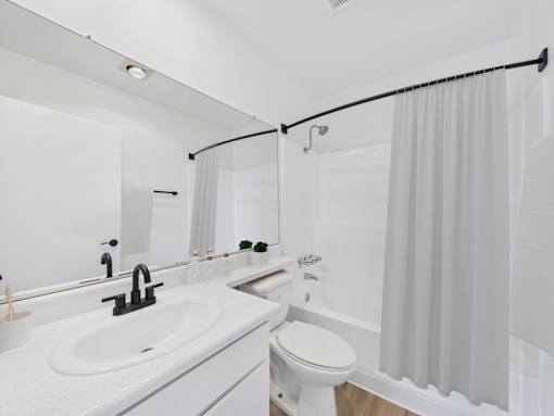 A white bathroom with a sink, toilet, and shower.